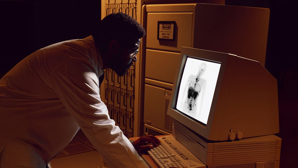 Radiologist reviewing scan of abdomen on early computer.