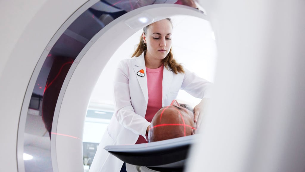 Technologist positioning patient for a SSTR PET scan with copper-based agent.