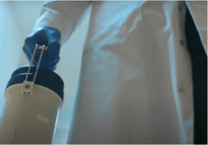 Oncology scientist handling a large sealed container.